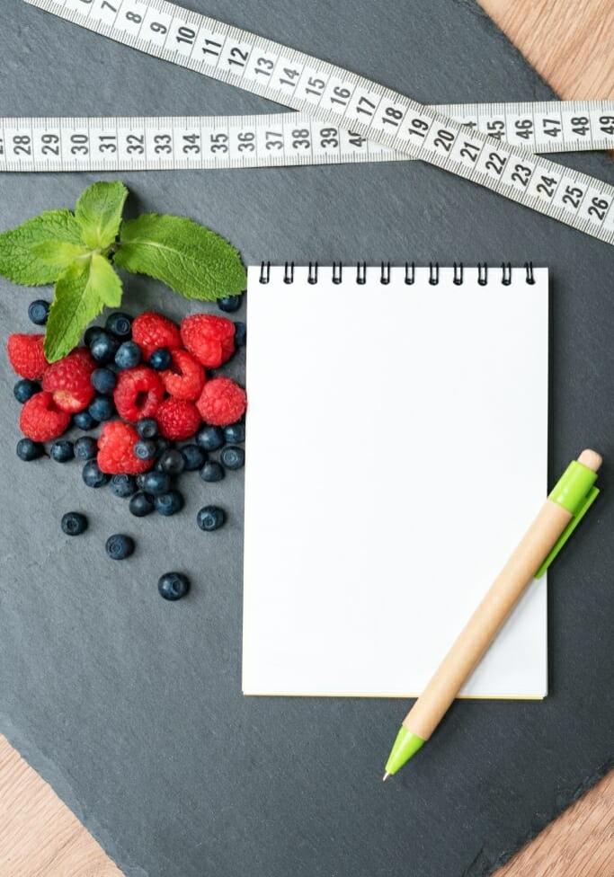 82981004 - blueberries, raspberries, mint, measuring tape and notepad for writing notes or resolutions, concept of sport, diet, slimming, detox, healthy lifestyles and nutrition. mock up, space for text.